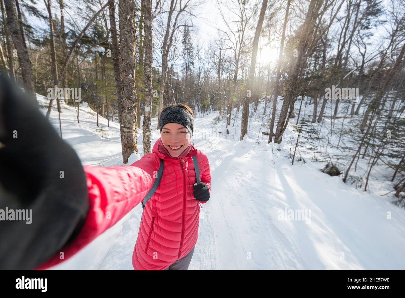 Inverno donna selfie telefono foto all'aperto trekking avventura nella foresta invernale coperta di neve. Asian attiva ragazza sorridente felice vivere sano attivo Foto Stock