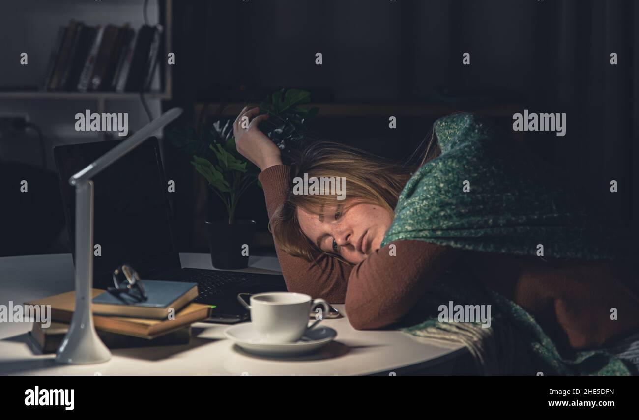 La giovane donna stanca sul posto di lavoro vuole dormire a tarda notte. Foto Stock