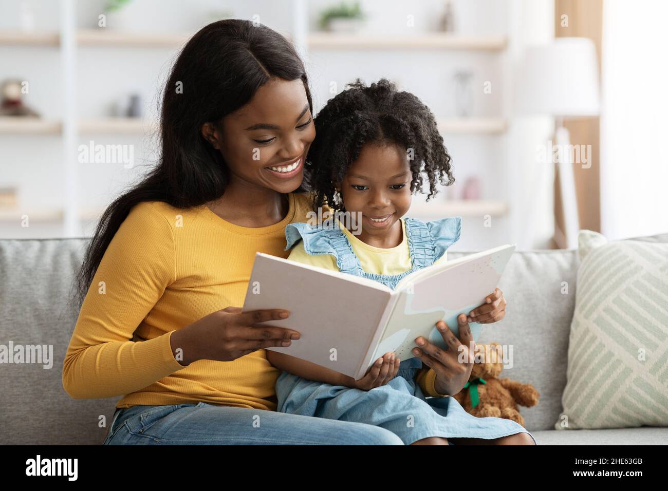 Amando libro di lettura della mamma nera alla sua figlia piccola carina nel paese Foto Stock