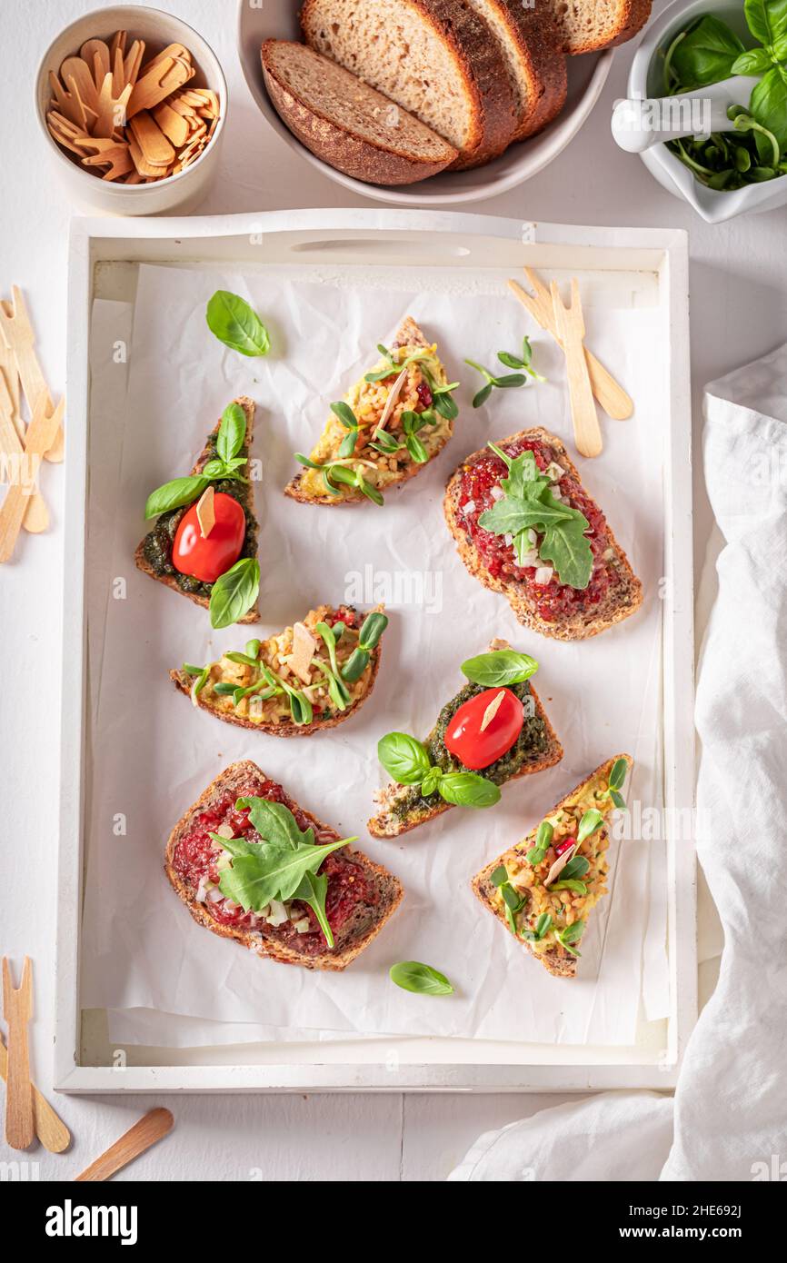 Bruschetta sana con pesto e pomodoro per colazione su un bordo di servizio. Foto Stock