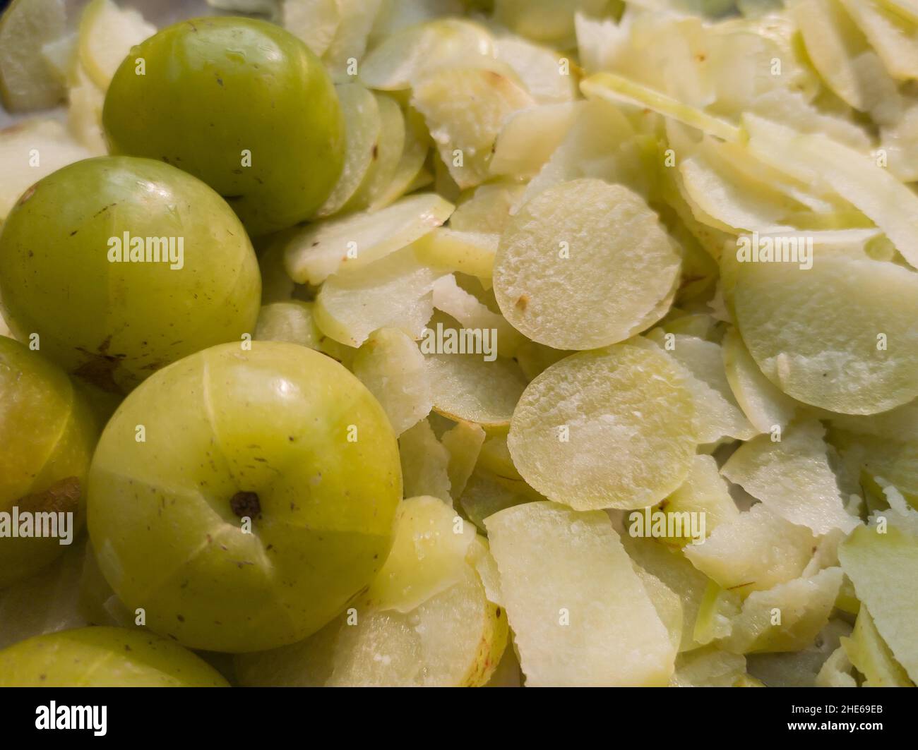 uva spina indiana o amla tenuta alla luce del sole per asciugare. fresco tritato uva spina cruda e uno intero. copia sfondo spazio. Foto Stock