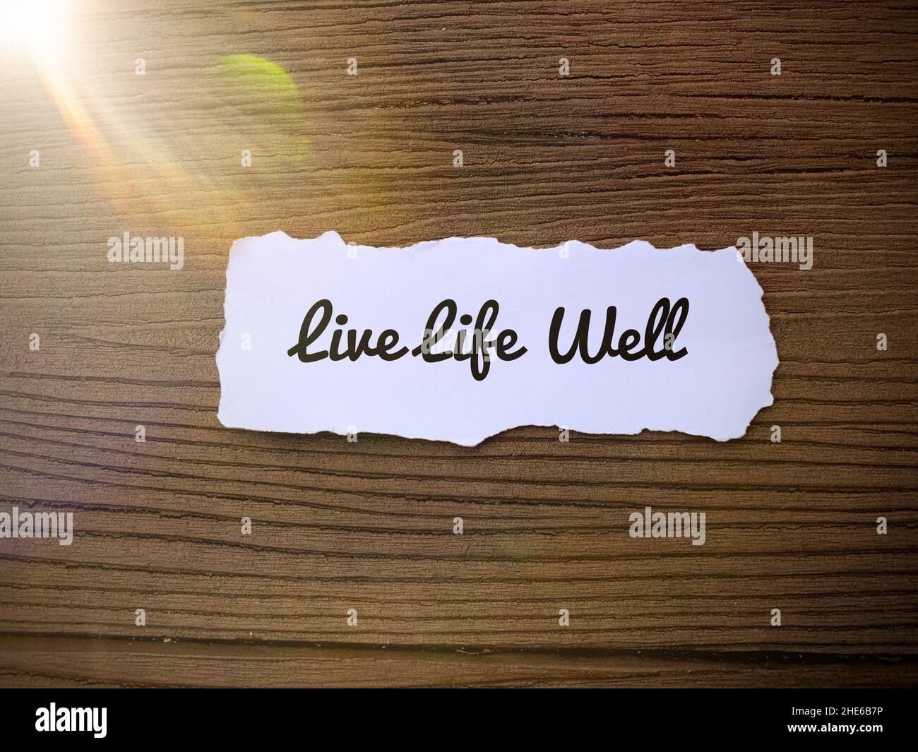 Citazioni motivazionali e ispiratrici - vivere bene la vita. Piccolo rip di carta e pavimento in legno sfondo. Foto Stock
