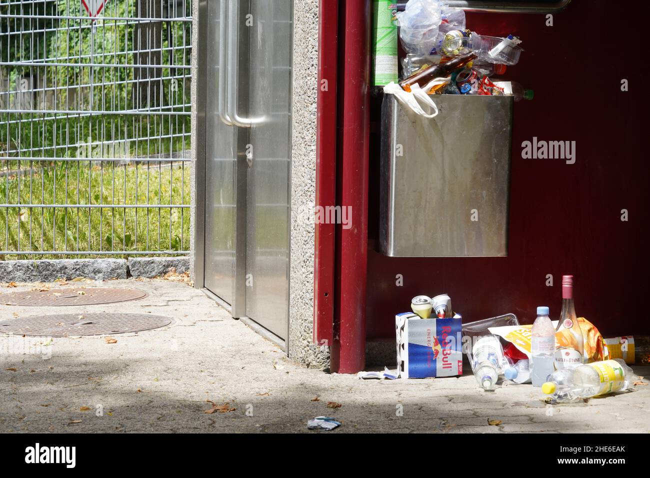 Rifiuti alimentari e altri rifiuti all'interno e intorno al cestino pubblico sulla fermata dell'autobus. Foto Stock