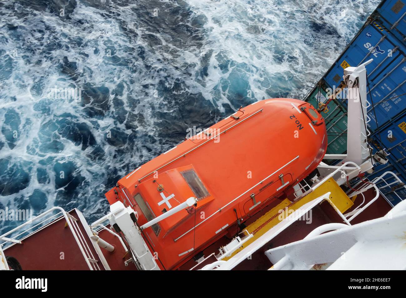 Imbarcazione a vita di colore arancione con nastro adesivo riflettente osservato dalla parte superiore fissato con i davits. Foto Stock