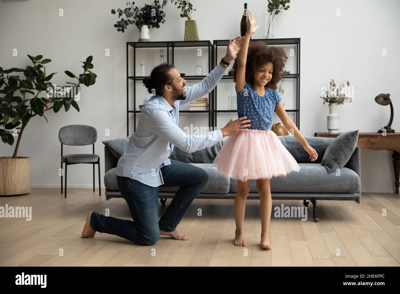 Papà allegro che aiuta la figlia in ballerina gonna per imparare la danza Foto Stock