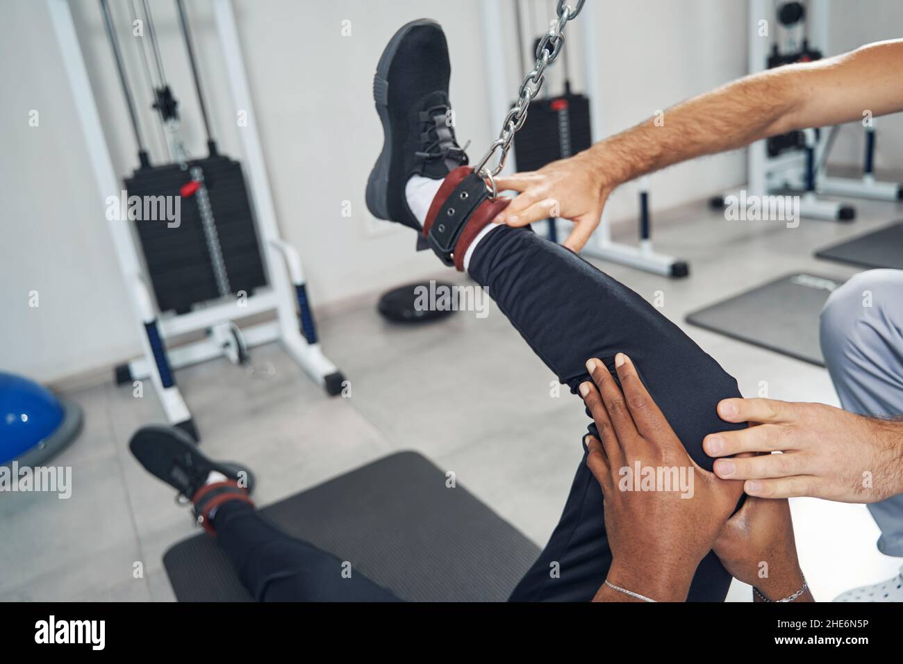 Paziente afroamericano che effettua l'esercitazione della gamba usando l'apparecchiatura della palestra Foto Stock