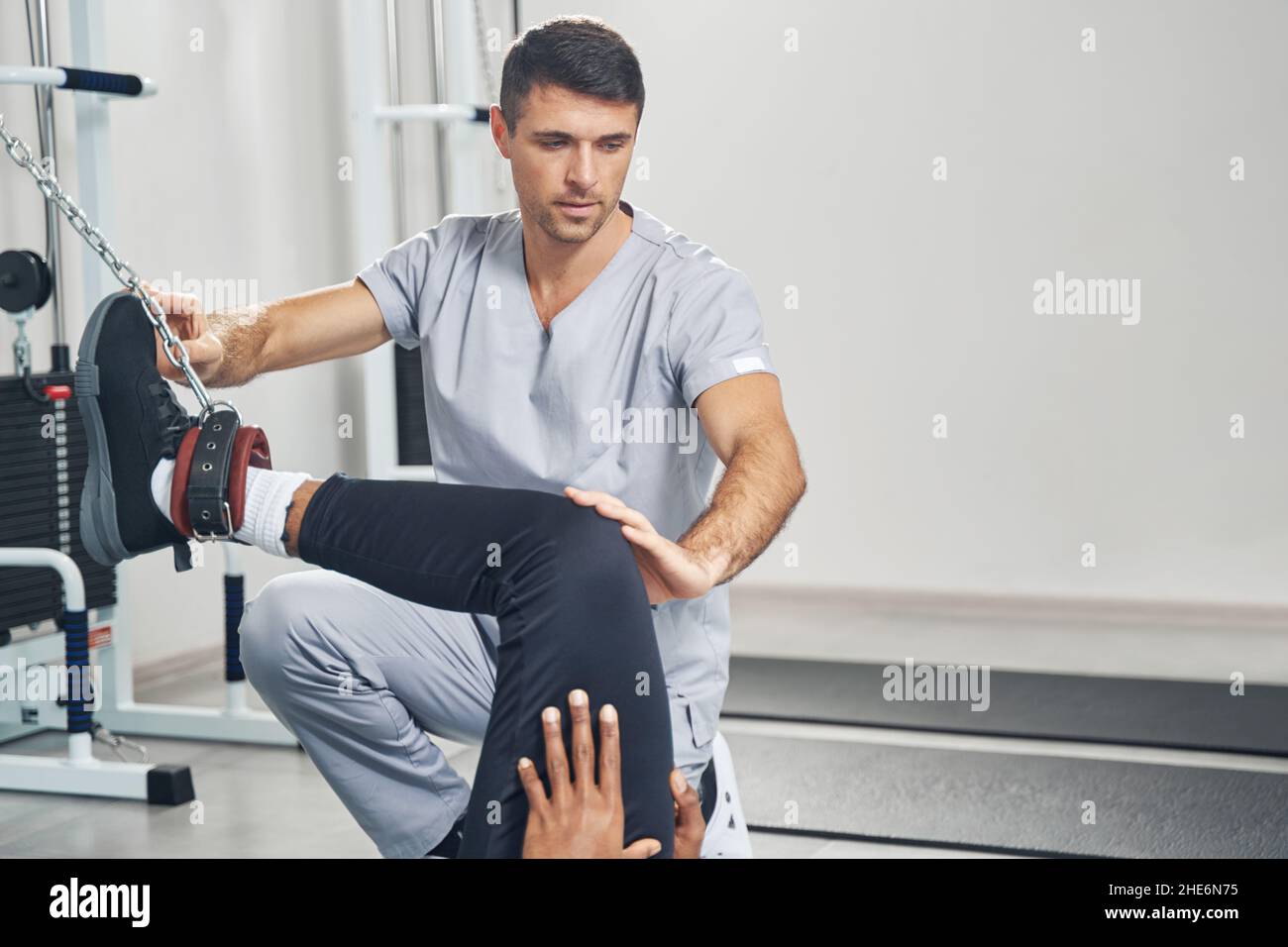 Medico che esegue la riabilitazione delle gambe di pazienti maschi Foto Stock