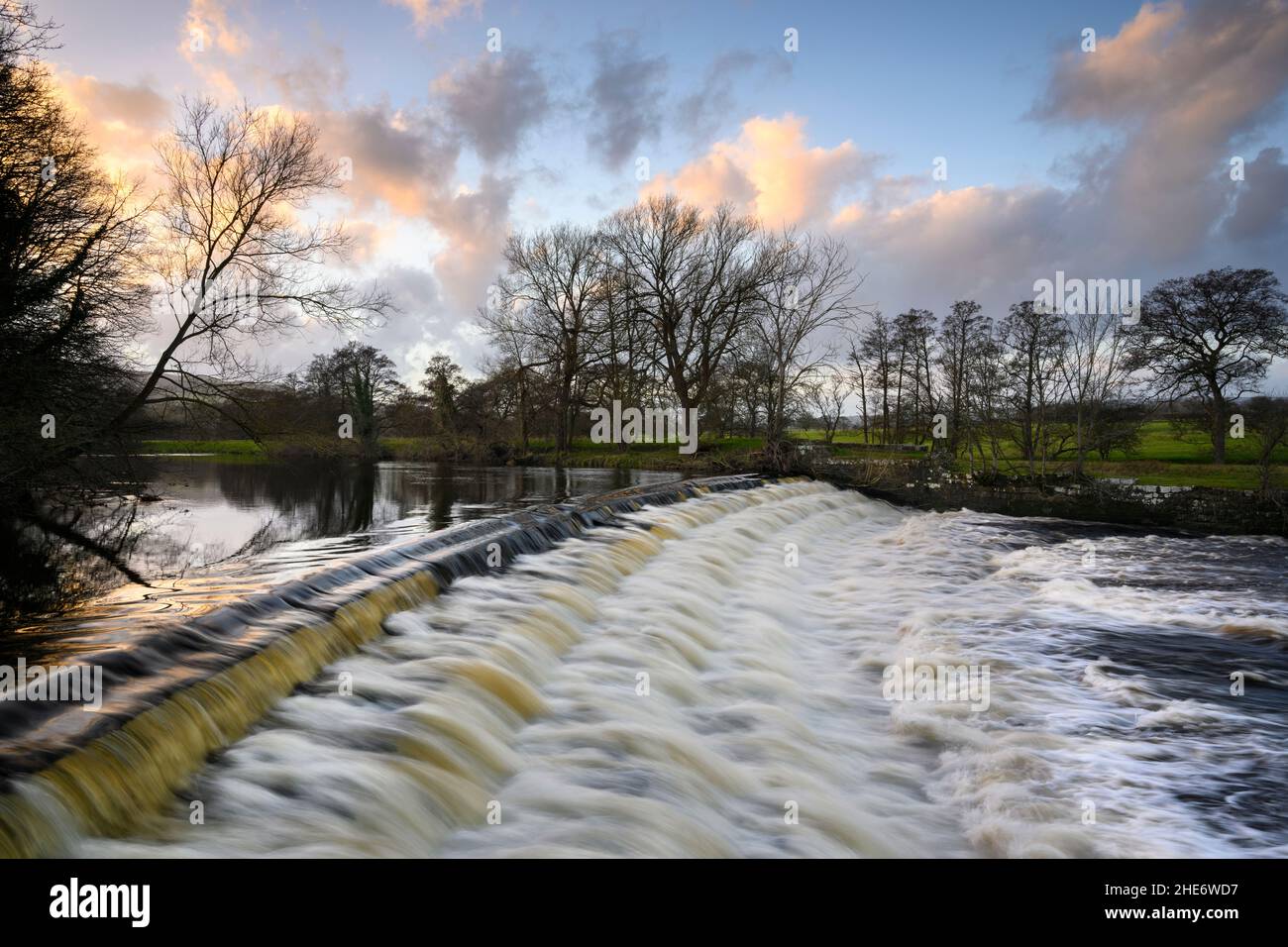 Scenico cielo colorato e paesaggio rurale (acqua che scende a passi di stramazzo, forza idraulica) - River Wharfe, Burley a Wharfedale, Yorkshire, Inghilterra, Regno Unito. Foto Stock