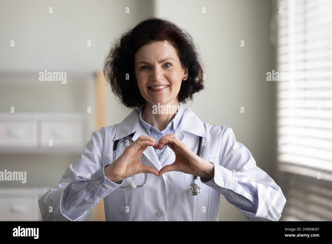 Felice bel medico di mezza età facendo gesto di cuore. Foto Stock