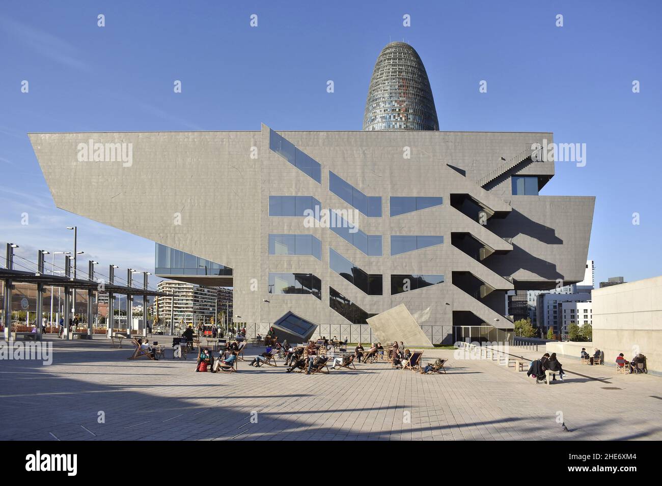 Persone su sedie rilassarsi fuori Museu del Disseny (Museo del Design) con grattacielo Torre Glories sullo sfondo, Barcellona Spagna. Foto Stock