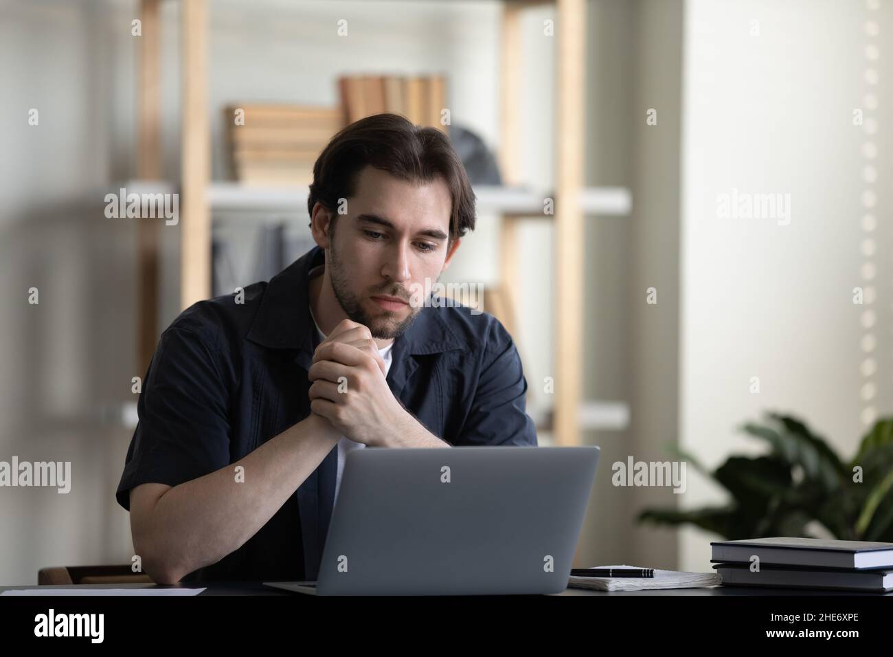 Giovane uomo d'affari premuroso che lavora al computer in ufficio domestico. Foto Stock