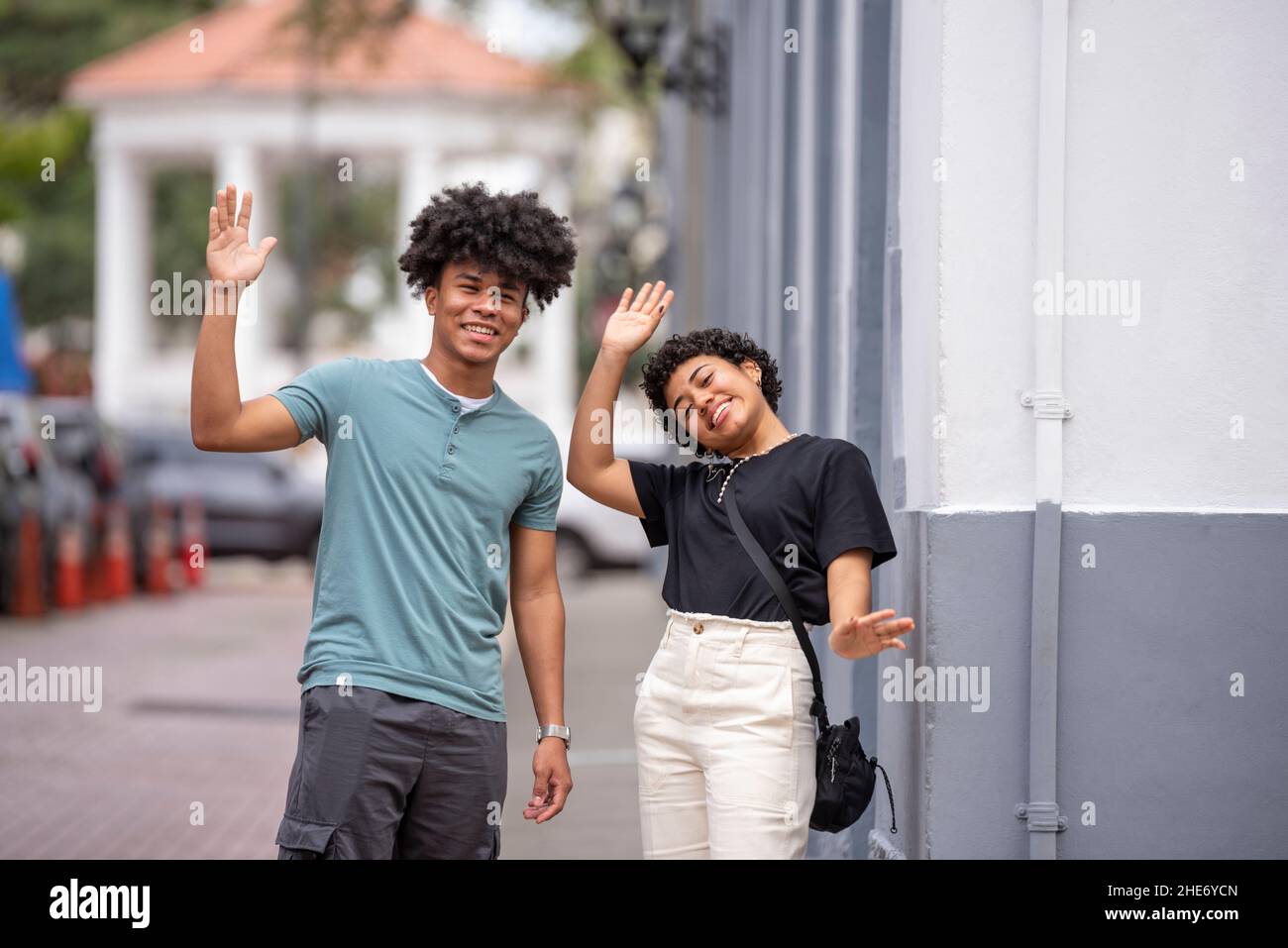 Coppia latina che sventolano le mani sul marciapiede, Città di Panama Foto Stock