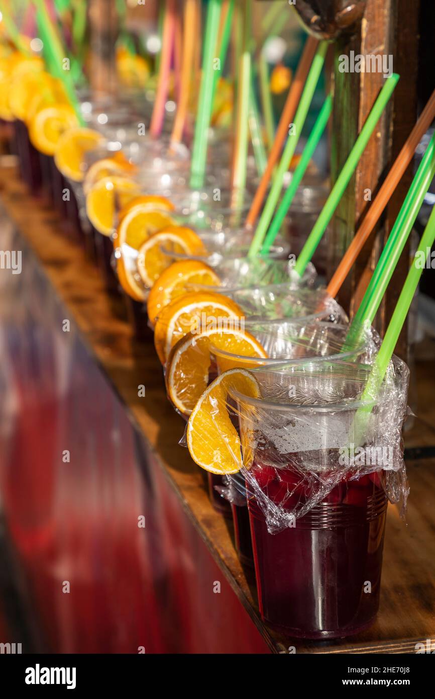 Primo piano in vista verticale di una fila di bicchieri di sangria con fette di arancia e cannucce colorate. Sangria è una bevanda rinfrescante nativa della Spagna A. Foto Stock