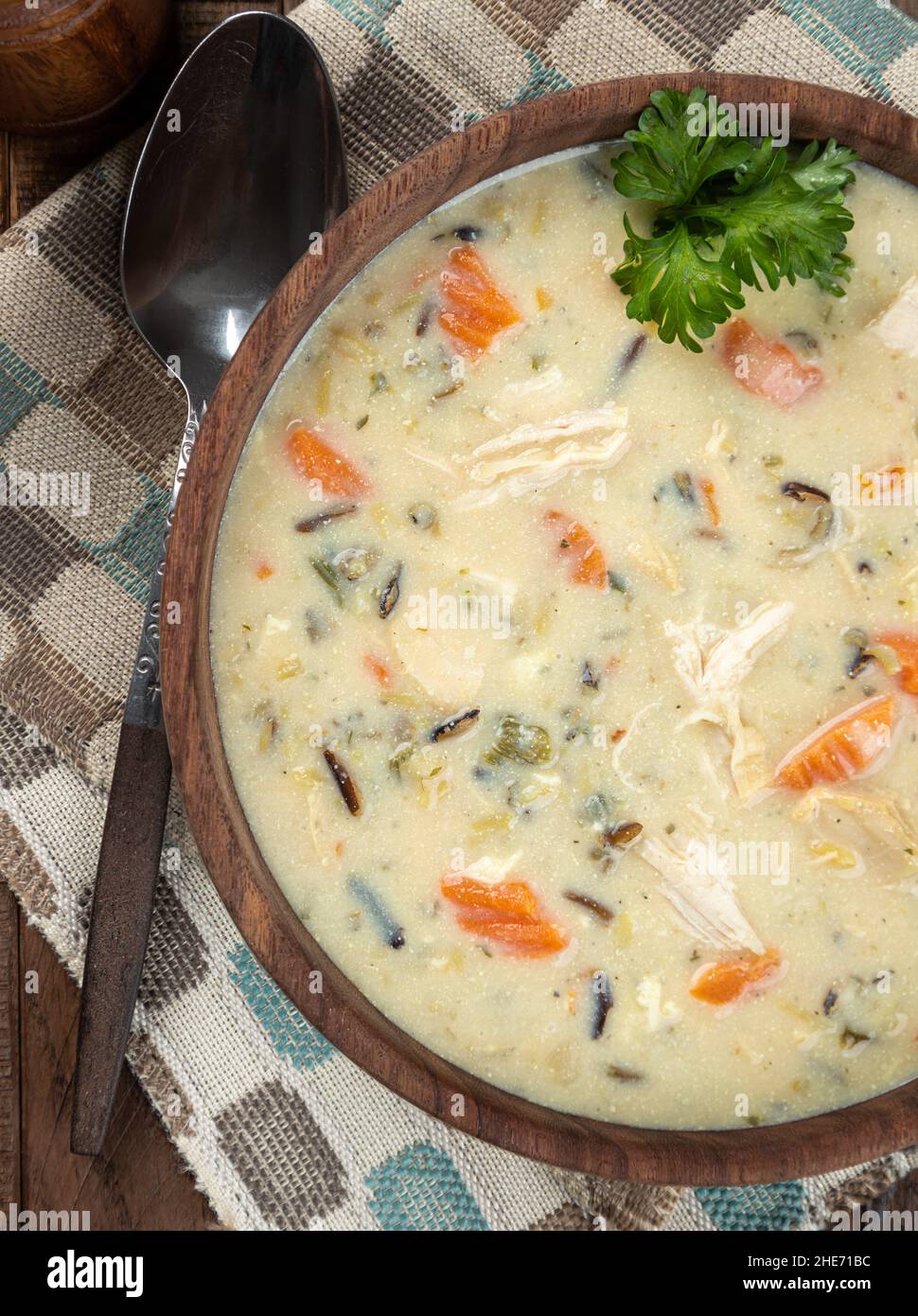 Ciotola di zuppa di pollo e riso con carote e guarnita con prezzemolo su un rustico tavolo di legno. Vista dall'alto Foto Stock