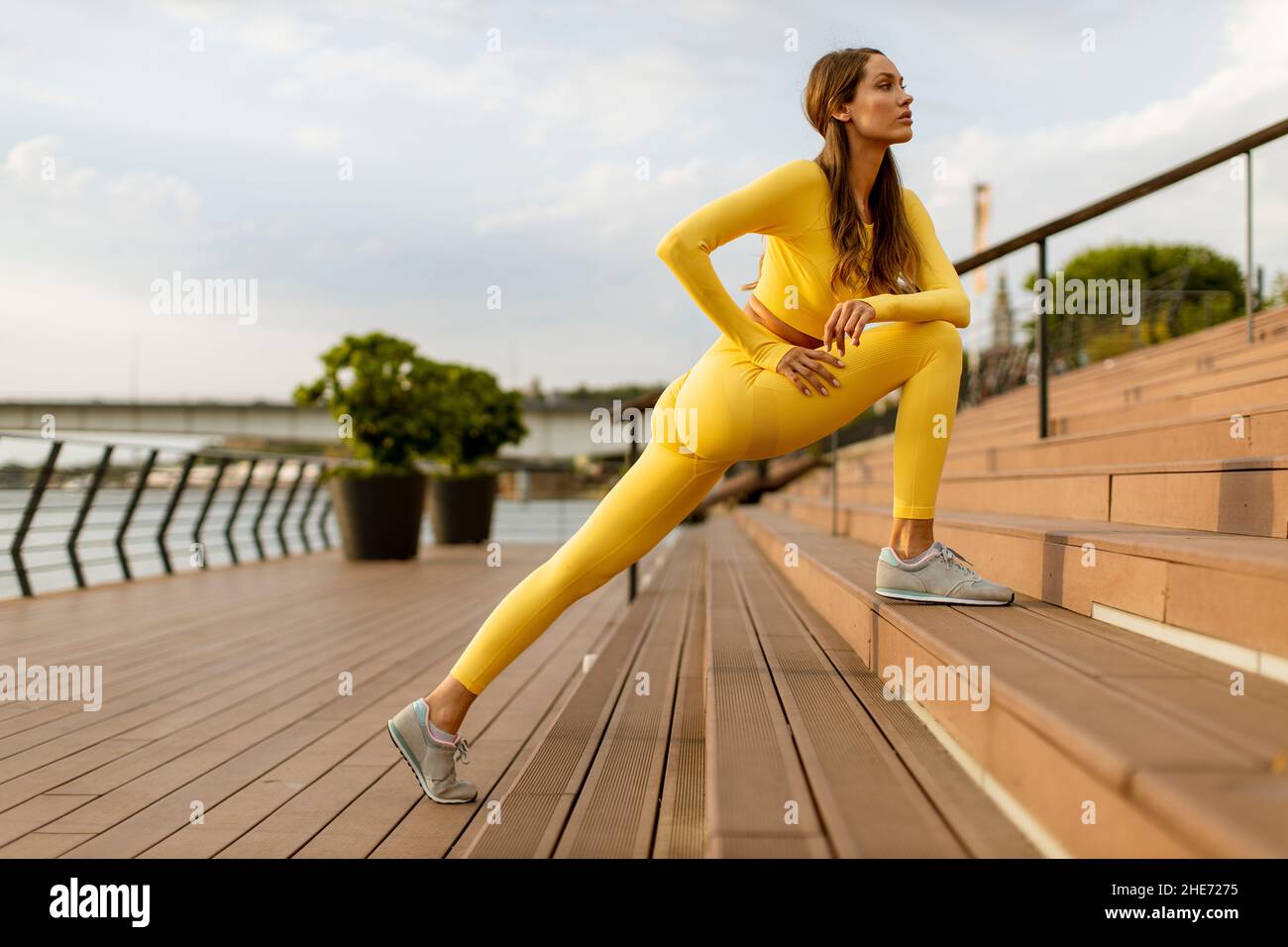 Bella giovane donna che ha stretching esercizio sul molo sul fiume Foto Stock
