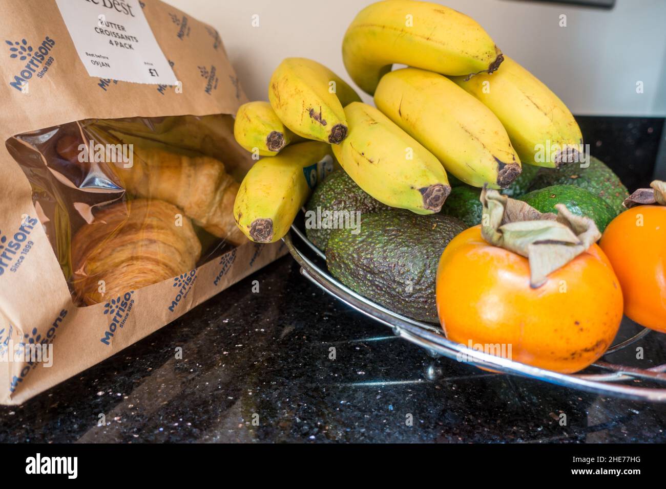 Shot lifestyle di frutta sana e croissant al forno sul piano della cucina Foto Stock