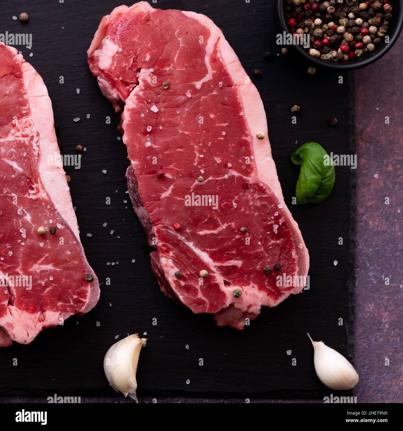 Top in basso da vicino vista di una bistecca di striploin crudo con condimento. Foto Stock