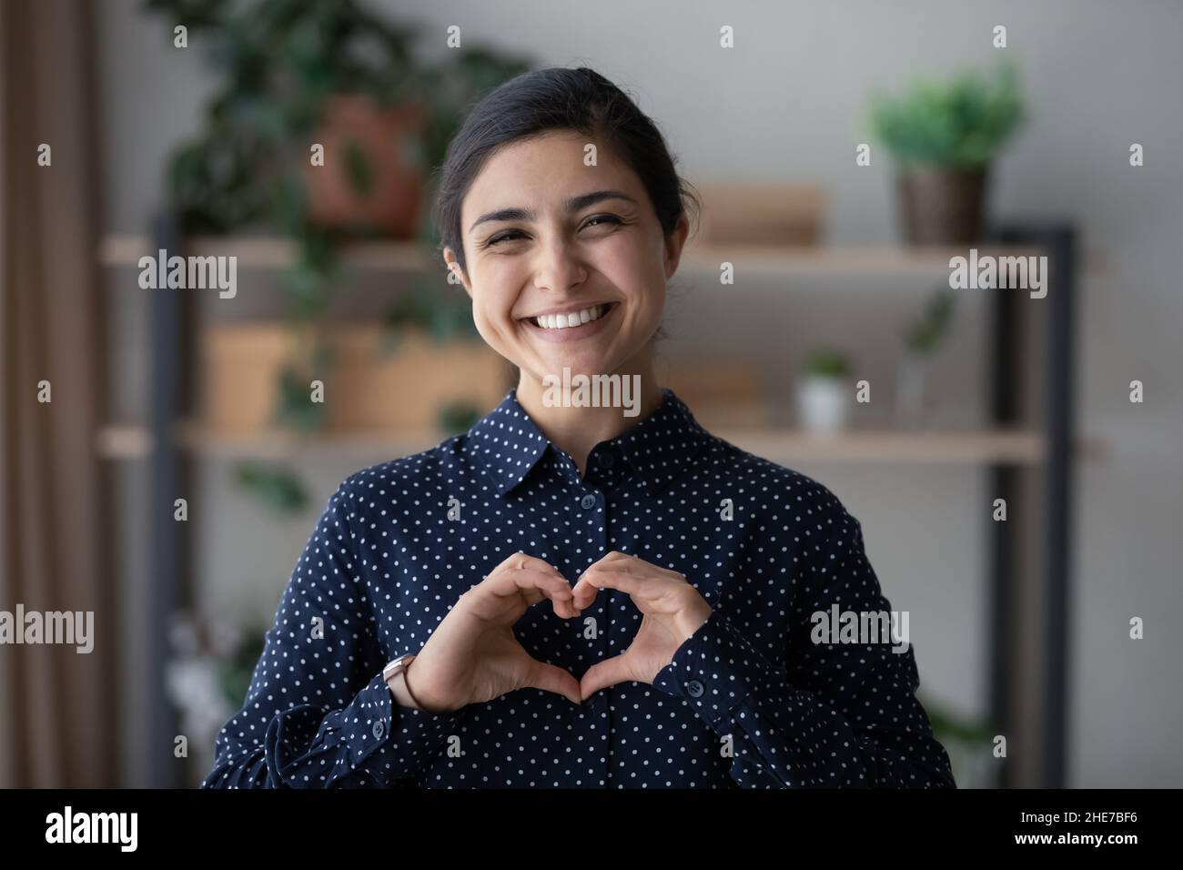 Felice donna indiana millenaria facendo mano dito cuore Foto Stock