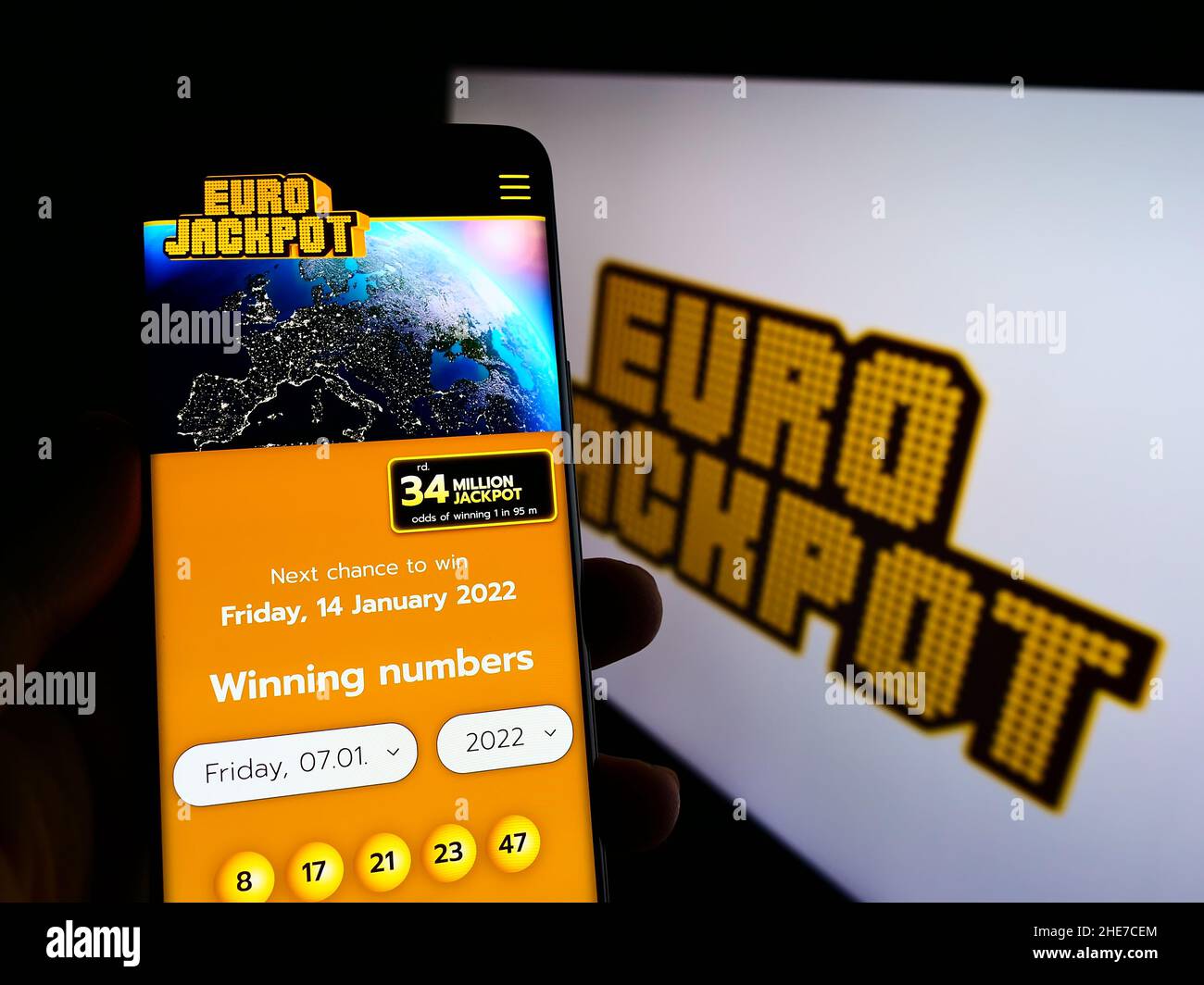 Persona che detiene il cellulare con sito web della lotteria europea transnazionale Eurojackpot sullo schermo di fronte al logo. Concentrarsi sul centro del display del telefono. Foto Stock