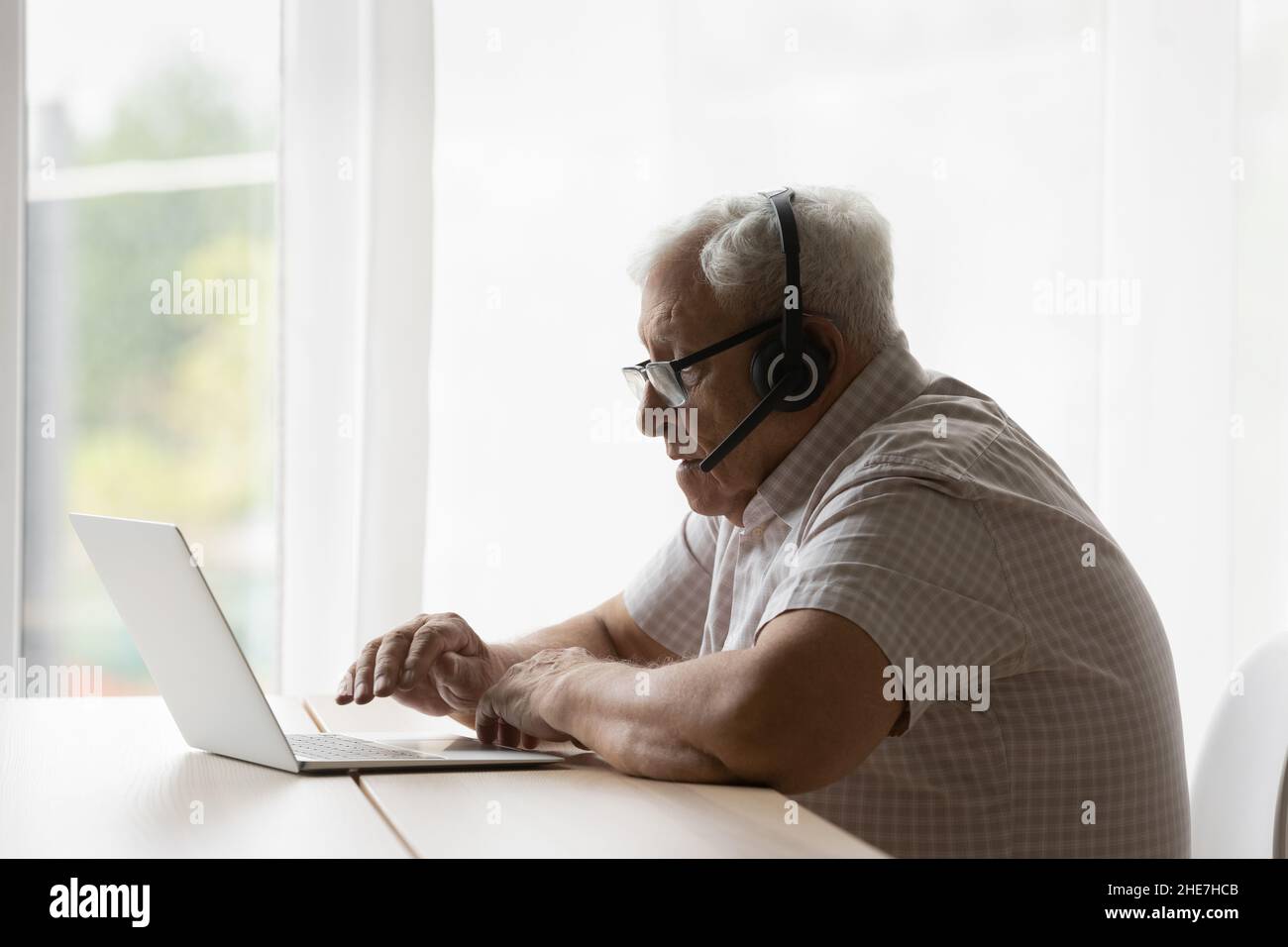 Concentrato 80s vecchio uomo in pensione che tiene una conversazione di videochiamata. Foto Stock