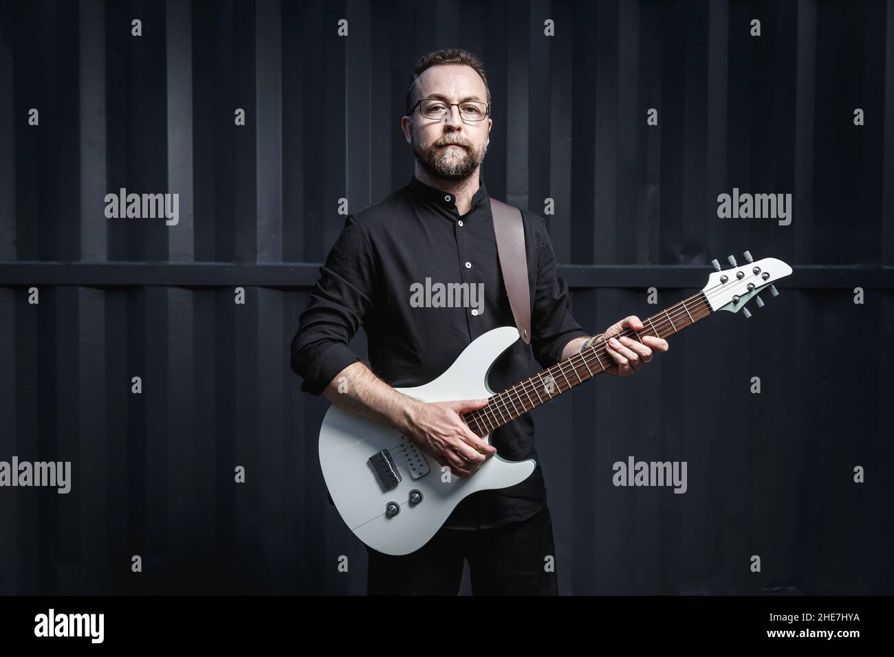 Ritratto di un chitarrista maschile con chitarra elettrica che indossa abiti neri. Concetto di carattere rock musicista Foto Stock