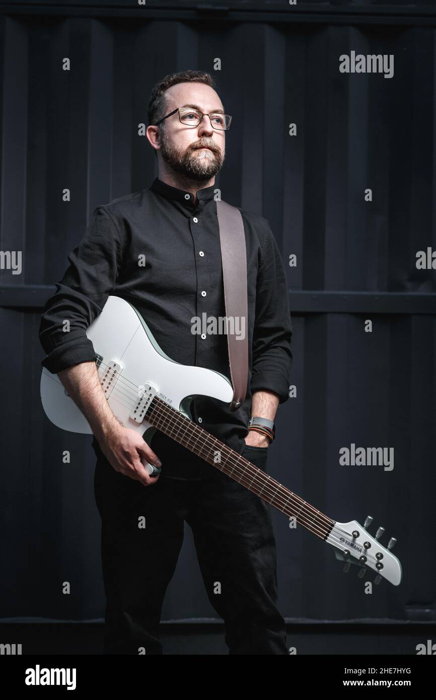 Ritratto di un chitarrista maschile con chitarra elettrica che indossa abiti neri. Concetto di carattere rock musicista Foto Stock