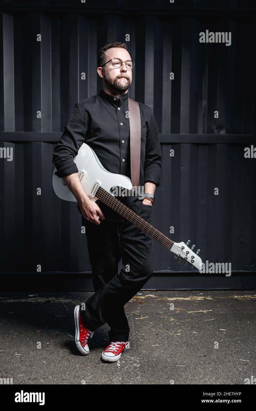 Ritratto di un chitarrista maschile con chitarra elettrica che indossa abiti neri. Concetto di carattere rock musicista Foto Stock