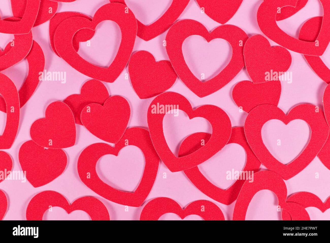 Molte carte a forma di cuore conferiscono cuori su sfondo rosa Foto Stock