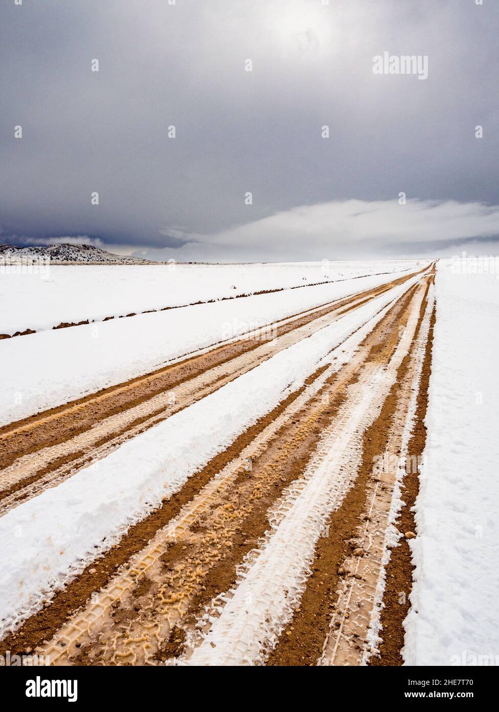 House Rock Road a nord dell'autostrada 89A in Arizona con copertura di neve e solchi. Nuvole tempesta invernale in lontananza. Foto Stock