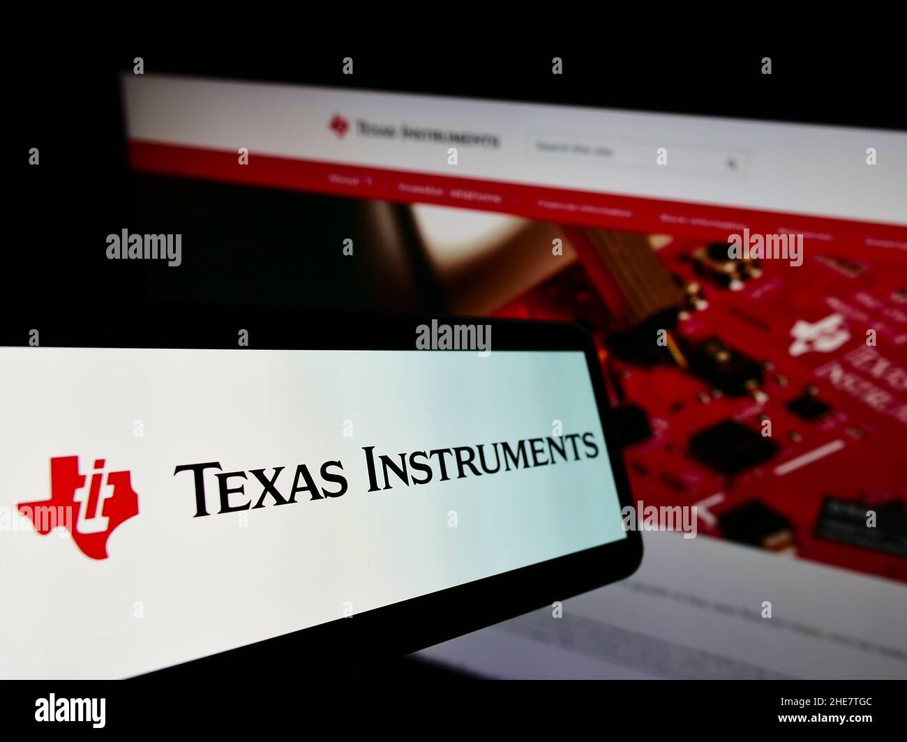 Telefono cellulare con logo della società statunitense Texas Instruments Incorporated (ti) sullo schermo di fronte al sito web. Messa a fuoco al centro-sinistra del display del telefono. Foto Stock