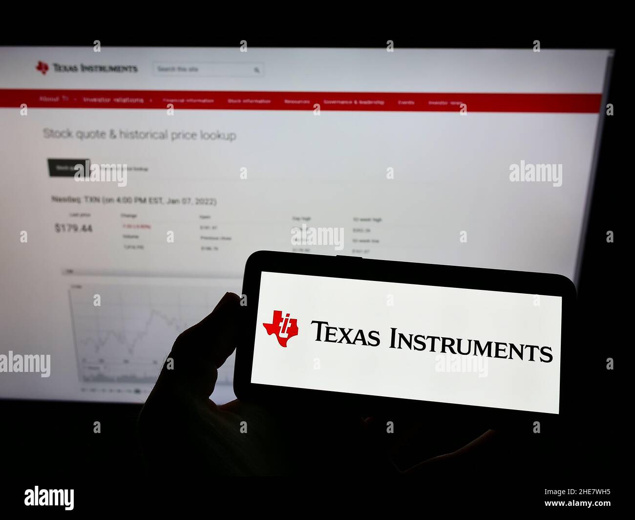 Persona che tiene il telefono cellulare con il logo della società statunitense Texas Instruments Incorporated (ti) sullo schermo di fronte alla pagina web. Mettere a fuoco sul display del telefono. Foto Stock