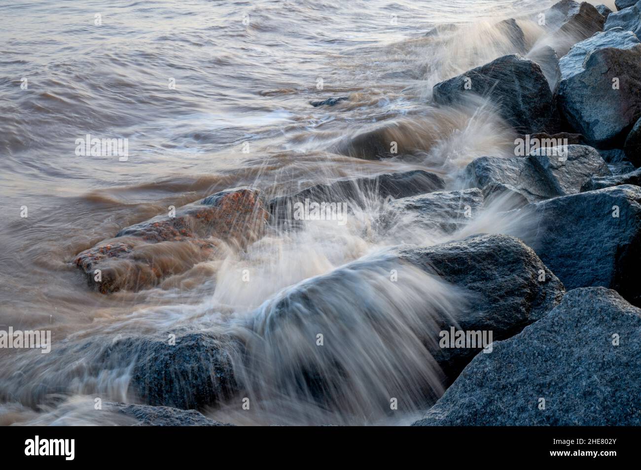 Onde che si infrangono sulle rocce delle difese marine a Skegness, Lincolnshire, Regno Unito Foto Stock
