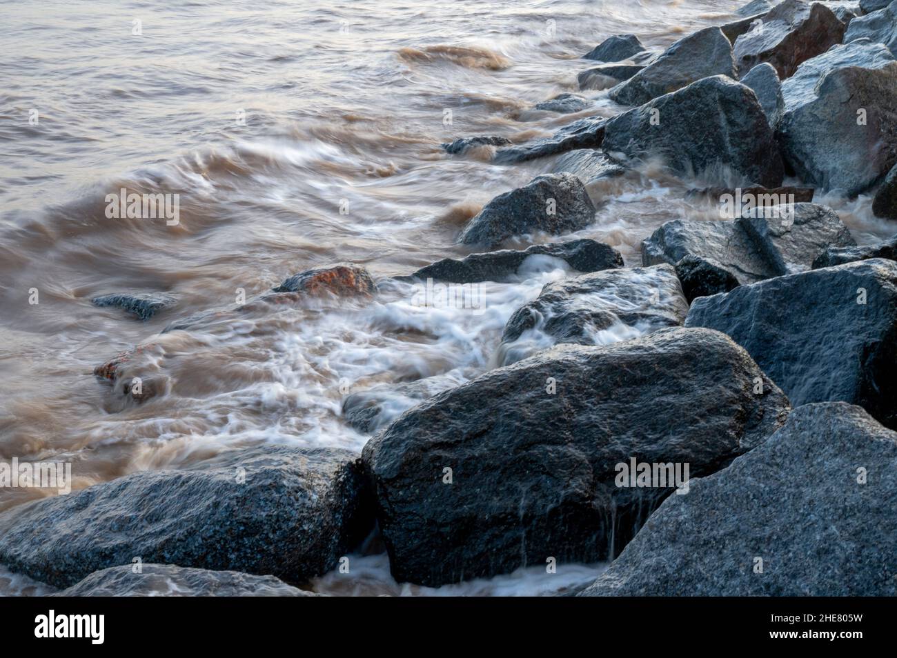 Onde che si infrangono sulle rocce delle difese marine a Skegness, Lincolnshire, Regno Unito Foto Stock