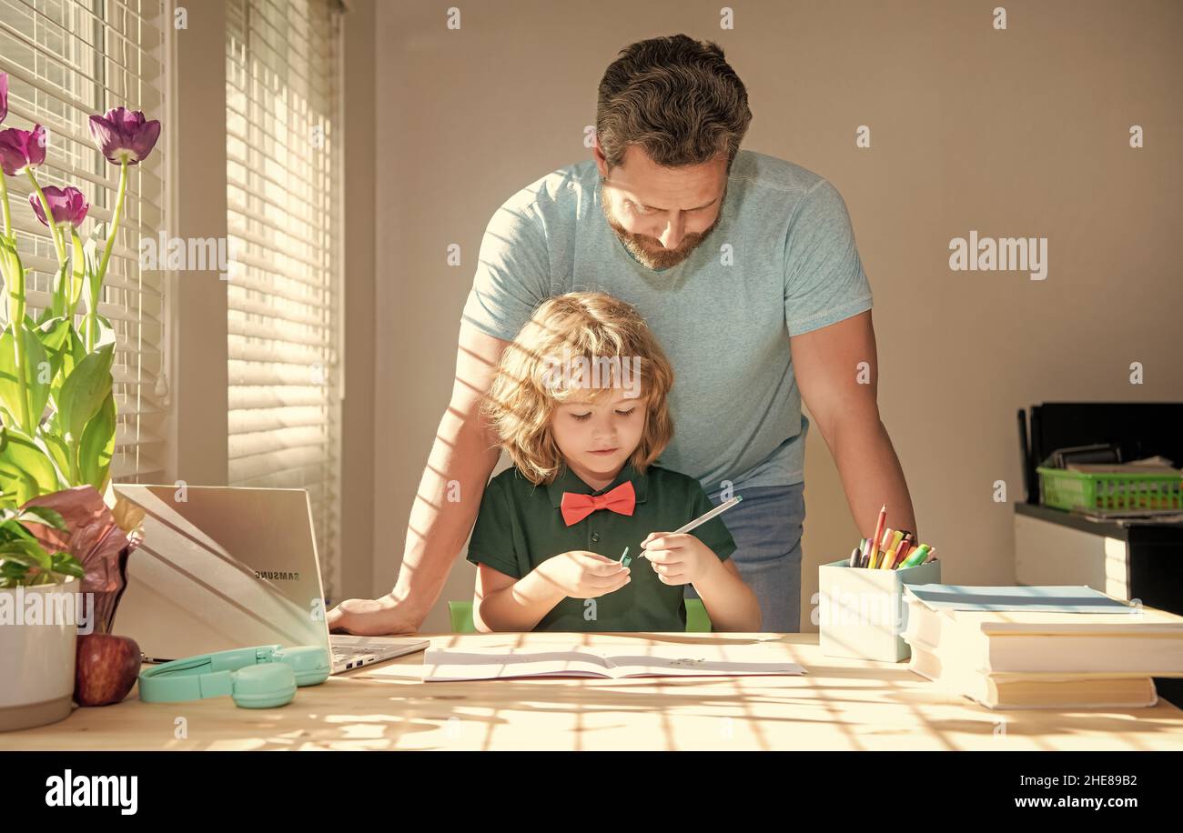 genitorialità. padre e figlio occupati che scrivono a casa. giorno della famiglia. ragazzo che studia con insegnante. Foto Stock