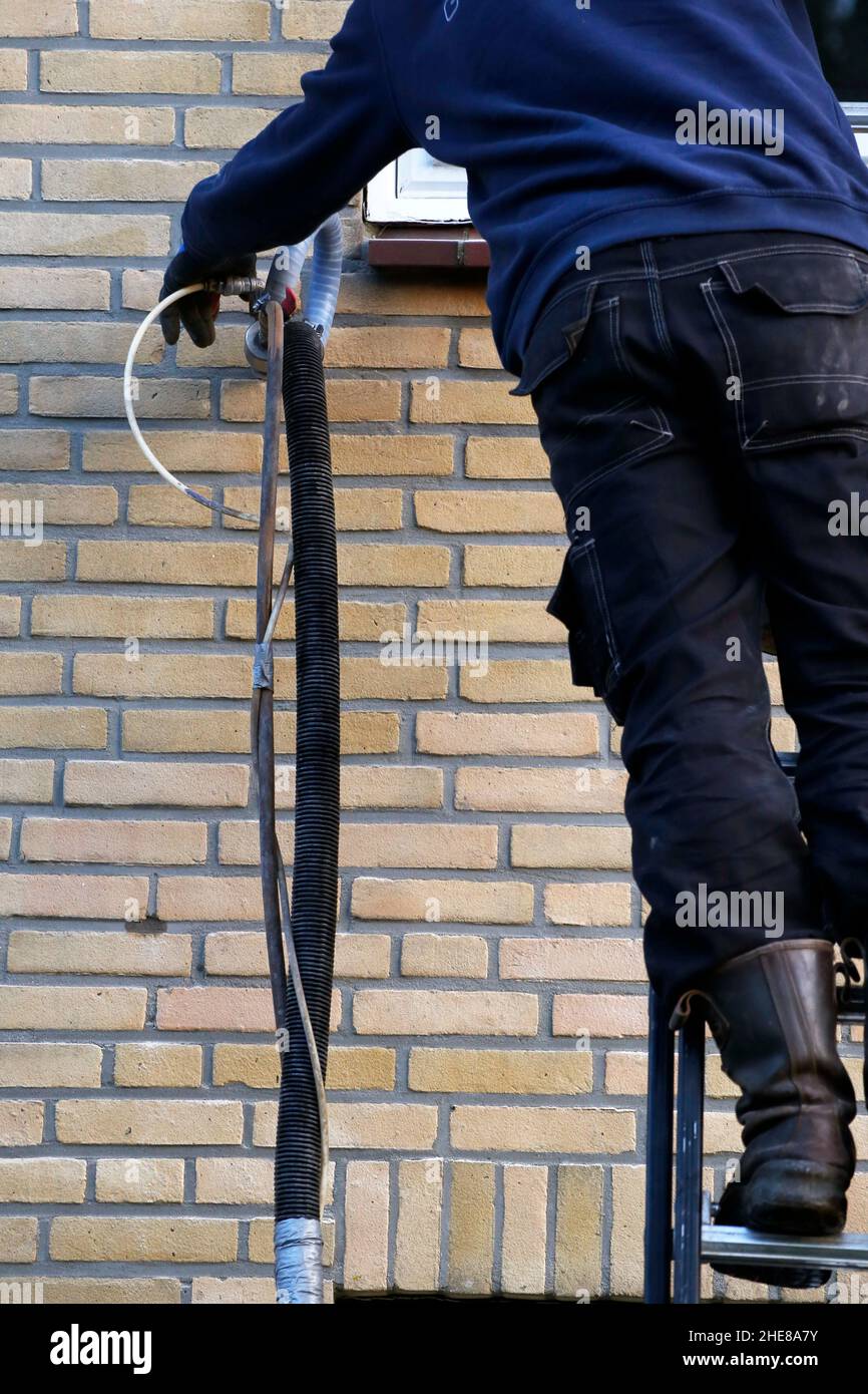 Isolamento della casa iniettando perle di microperline nelle pareti della cavità Foto Stock