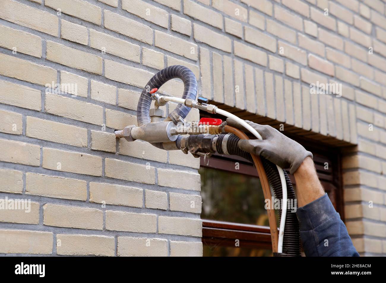 Isolamento della casa iniettando perle di microperline nelle pareti della cavità Foto Stock