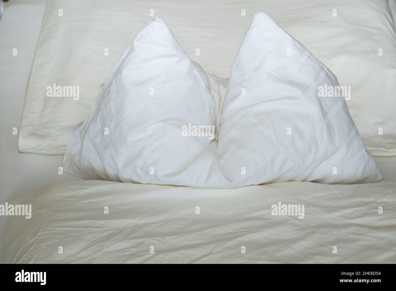 Cuscino bianco con pieghe in letto bianco - lenzuola Foto Stock
