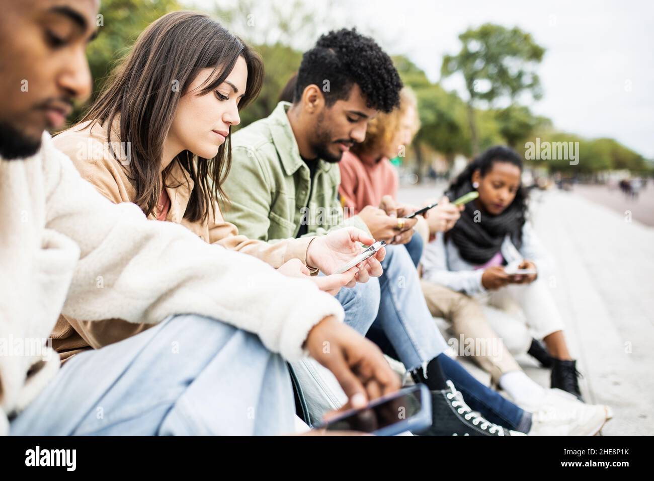 Studenti multirazziali addicted che utilizzano telefoni cellulari all'aperto Foto Stock