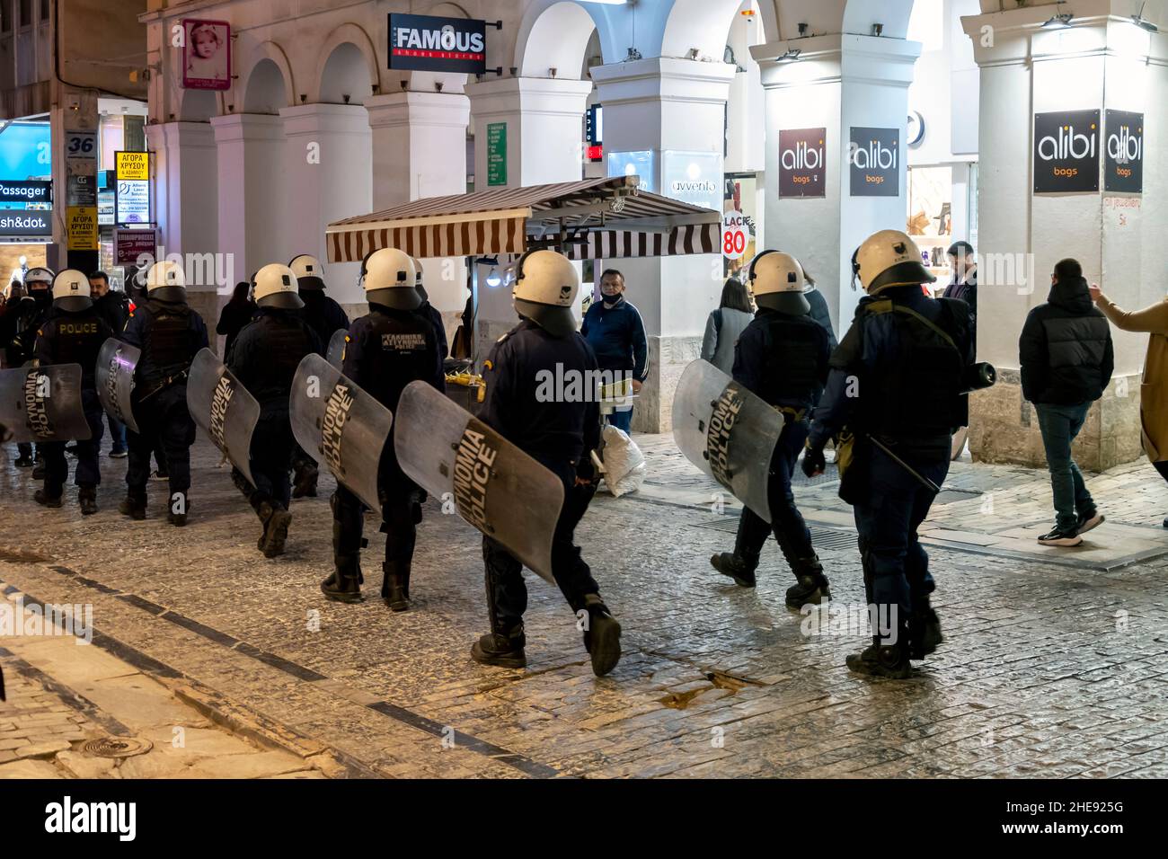 File di riordinamento ellenico polizia marcia attraverso il distretto centrale di Monastiraki di notte ad Atene, in Grecia, durante una convida protesta del 19. Foto Stock