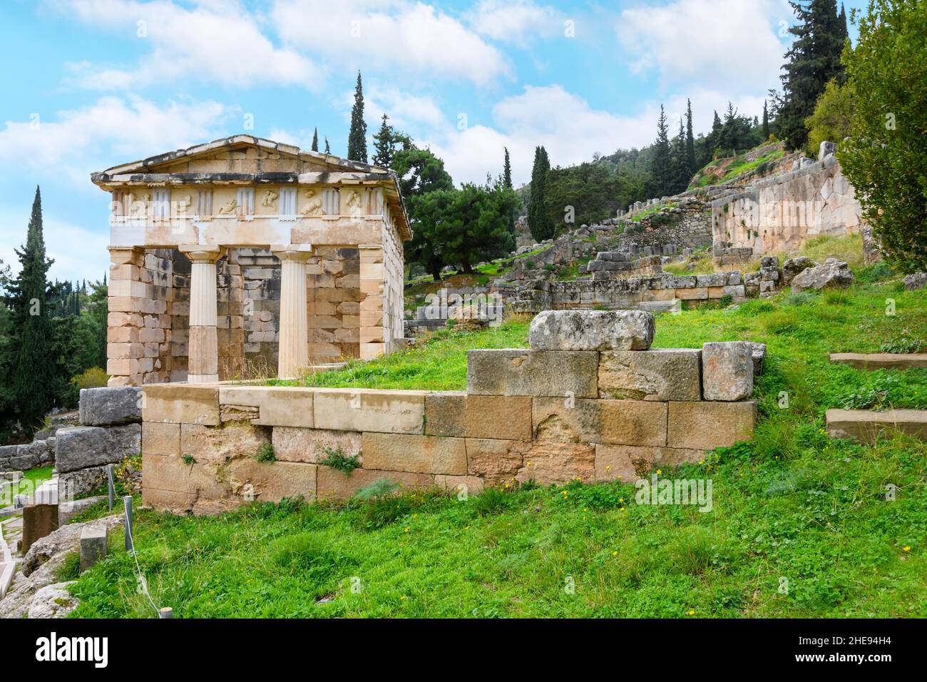 Vista della montagna e delle rovine presso l'antico sito oracolo di Delfi, Grecia, con il Tesoro Ateniano in primo piano. Foto Stock