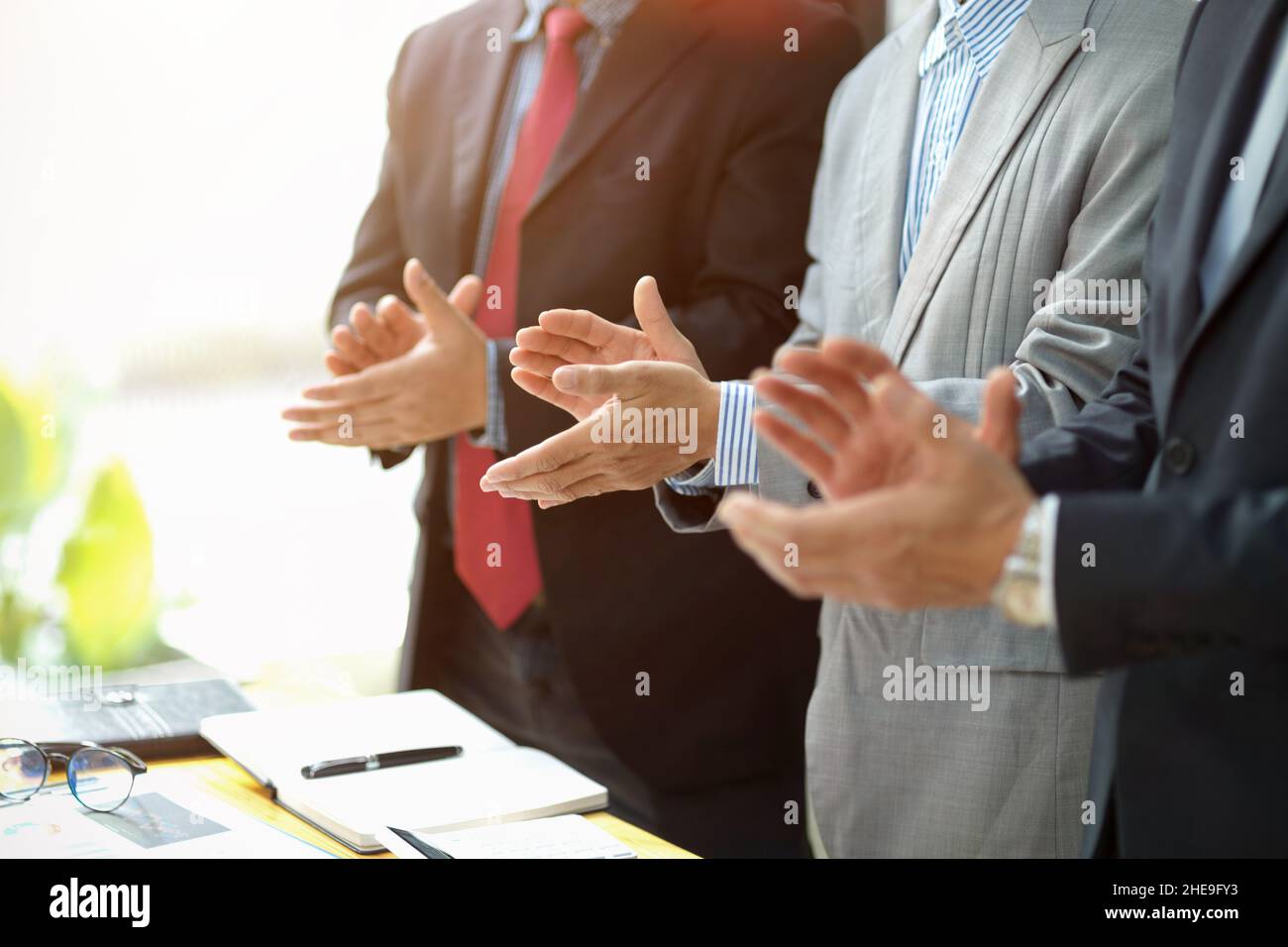 Gruppo di un dirigente d'affari che si alza e si aggrappa le mani nella sala riunioni. Congratulazioni, gesto di successo Foto Stock