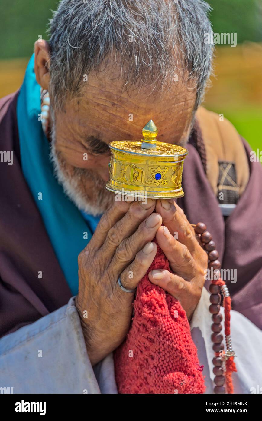 Pellegrino che prega con la ruota di preghiera al National Memorial Chorten, Thimphu, Bhutan Foto Stock