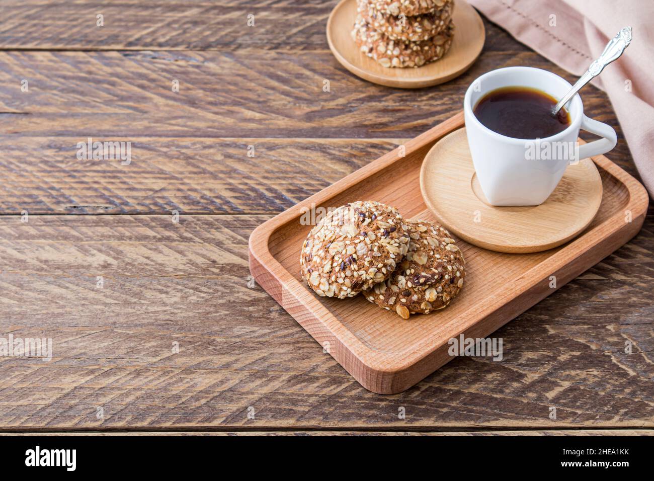 I biscotti dietetici fatti di farinata d'avena con semi di sesamo e lino vengono serviti per colazione su un vassoio di legno con caffè appena macinato Foto Stock