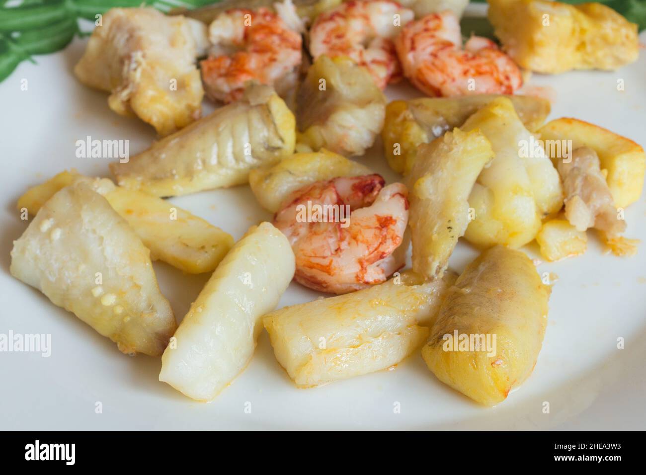 Alcuni pesci e frutti di mare in salsa su un piatto elegante. Cibo tradizionale. Foto Stock