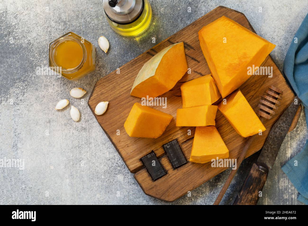 Zucca cruda e miele per preparare la cottura su sfondo di pietra grigia. Vista dall'alto, disposizione piatta. Spazio di copia. Foto Stock