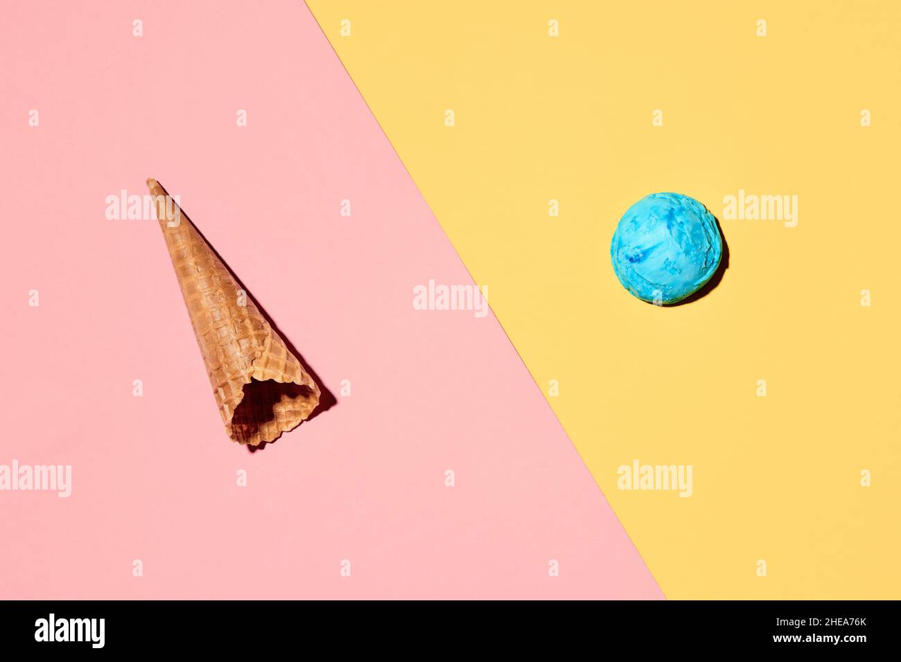 Cono gelato con cucchiaio di gelato su sfondo rosa pastello e giallo. Concetto minimo di cibo estivo. Disposizione piatta. Foto Stock