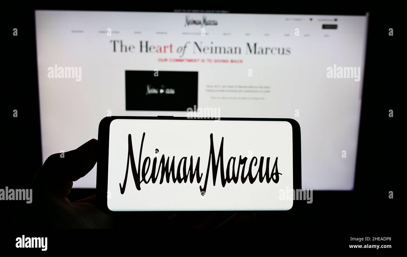 Persona che tiene uno smartphone con il logo del rivenditore di lusso statunitense Neiman Marcus Group Inc. Sullo schermo di fronte al sito Web. Mettere a fuoco sul display del telefono. Foto Stock