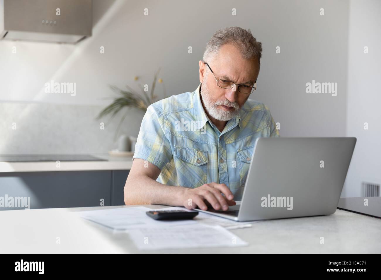 Uomo pensionato di mezza età concentrato che calcola il budget. Foto Stock