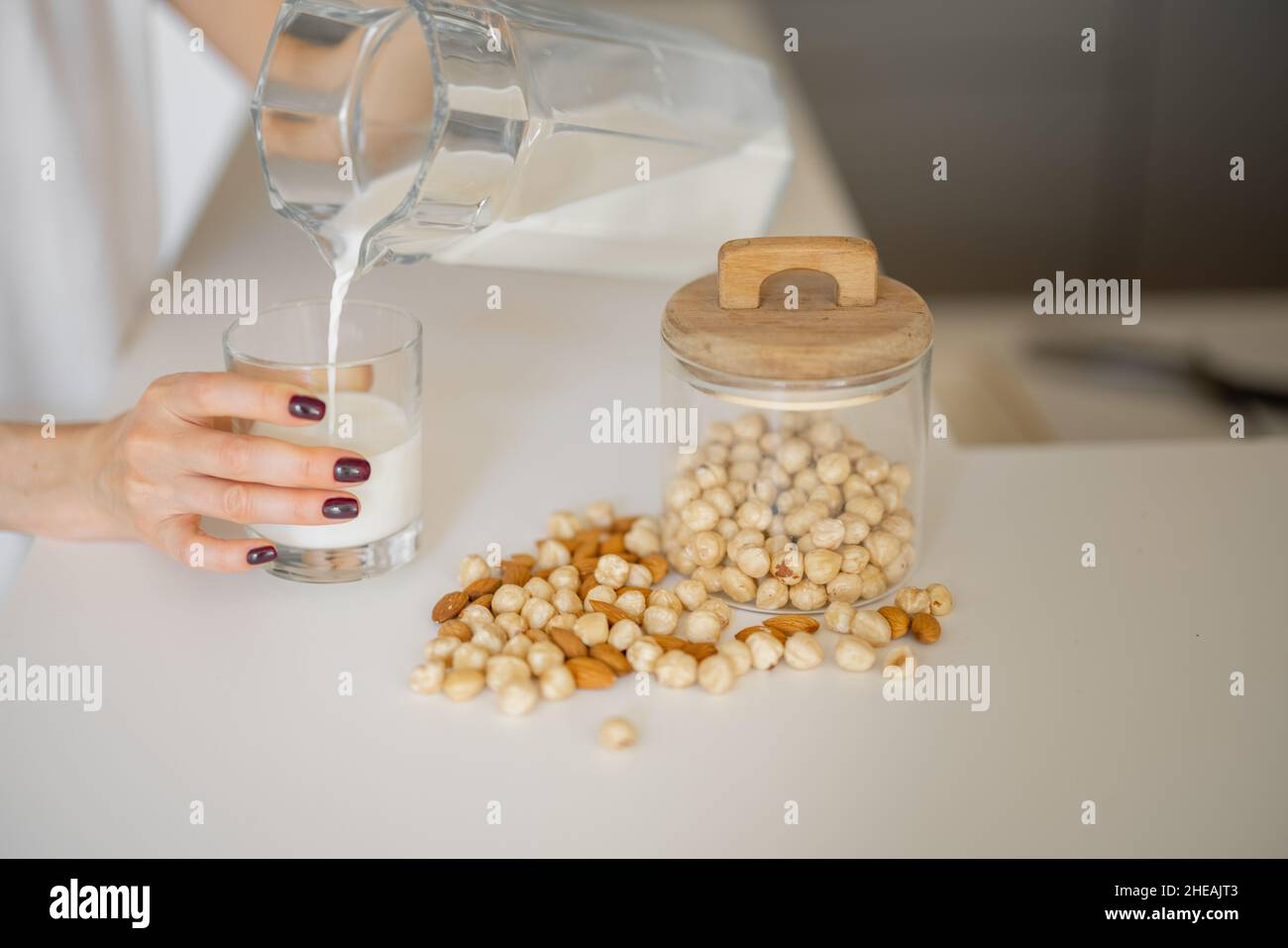 La donna beve latte vegetale a casa Foto Stock