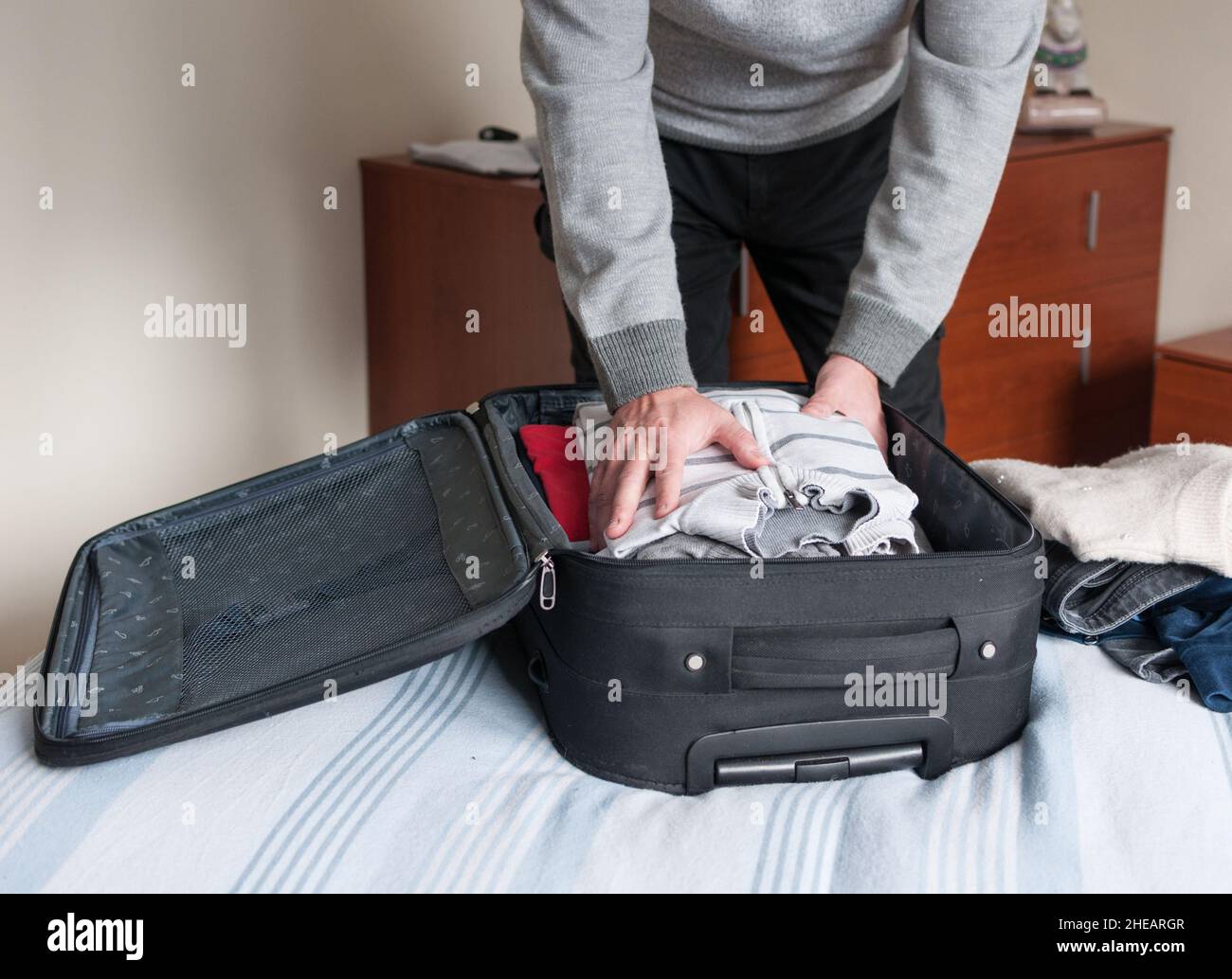 l'uomo prepara la valigia appoggiata sul letto Foto Stock